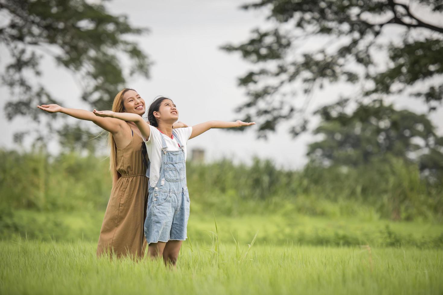 Mother and daughter standing happy in grass field photo