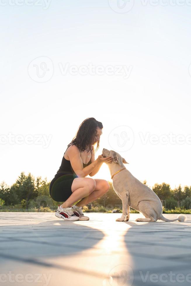 Atractiva mujer joven abrazando a su perro en el parque foto