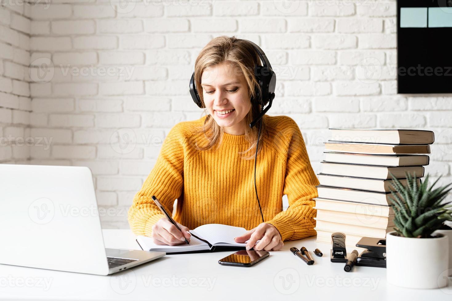 Young woman in black headphones studying online using laptop photo