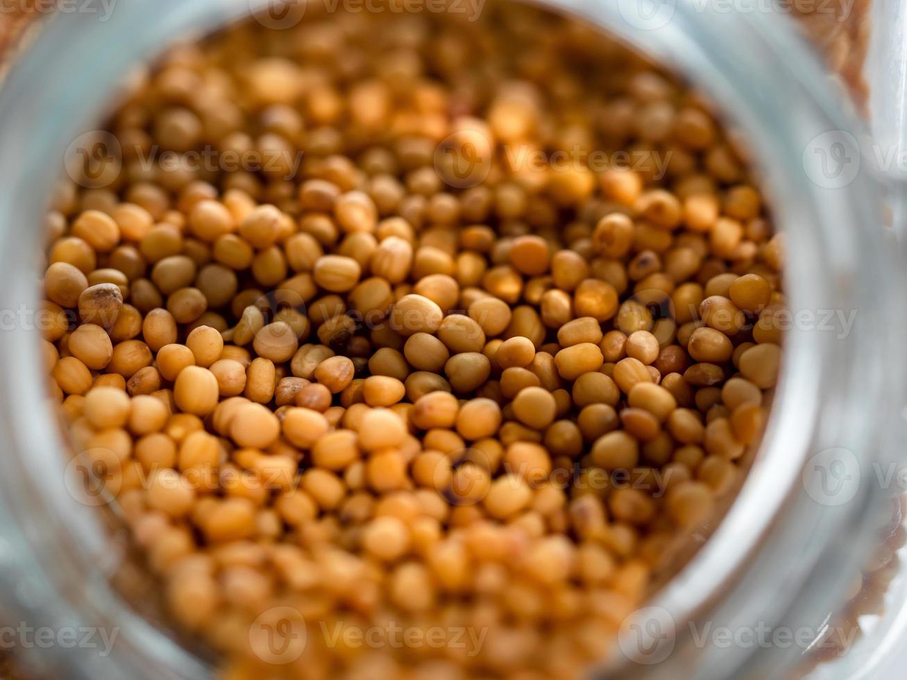 semillas de mostaza secas en una botella de vidrio. macro de primer plano. muchos detalles foto