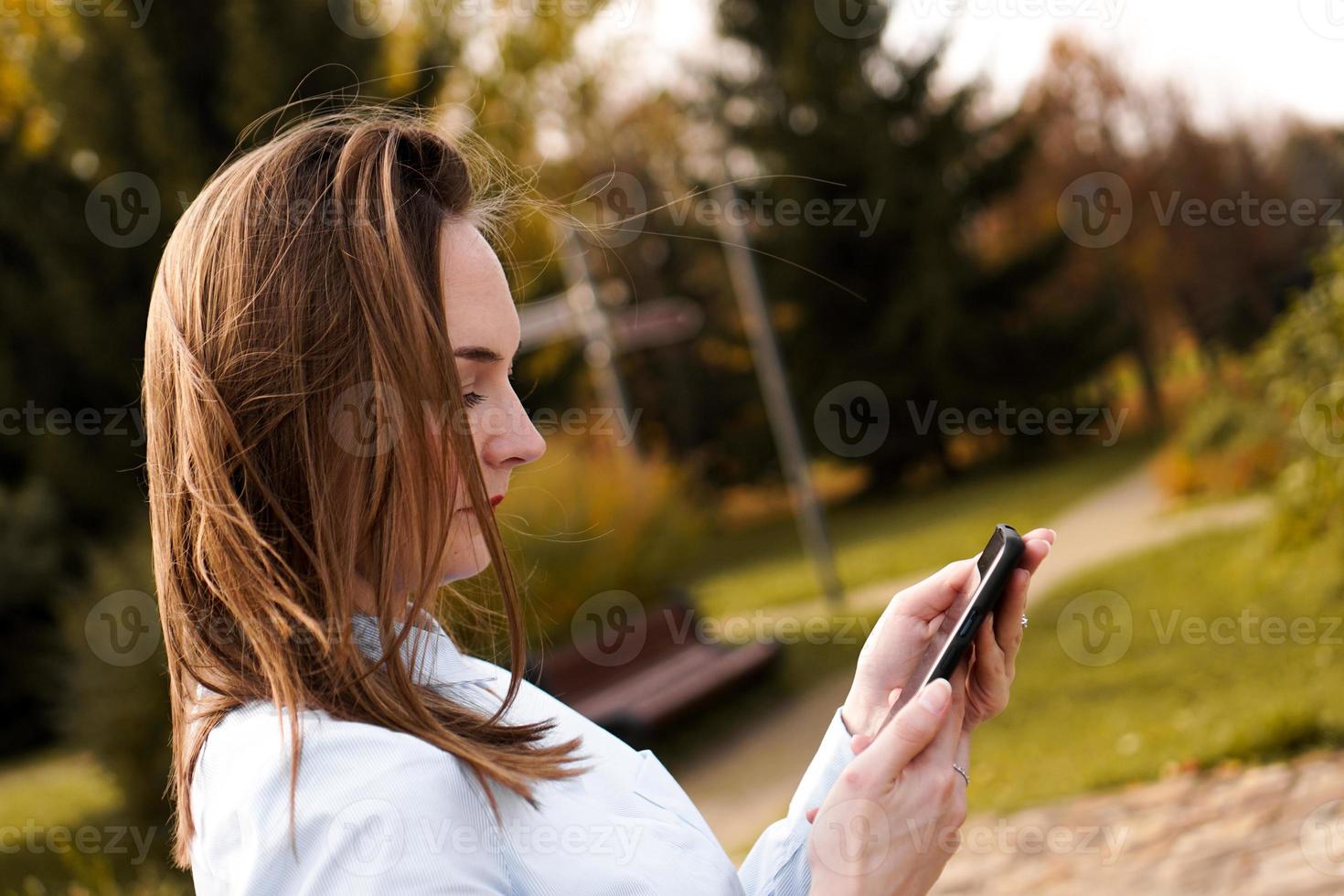 Mujer con teléfono inteligente móvil en el parque foto