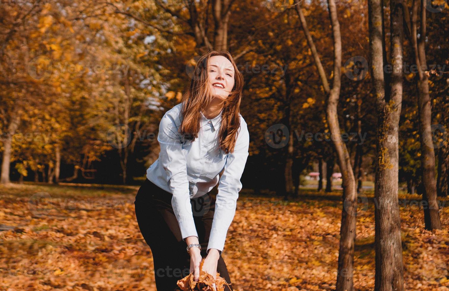 mujer lanzando hojas amarillas al aire foto