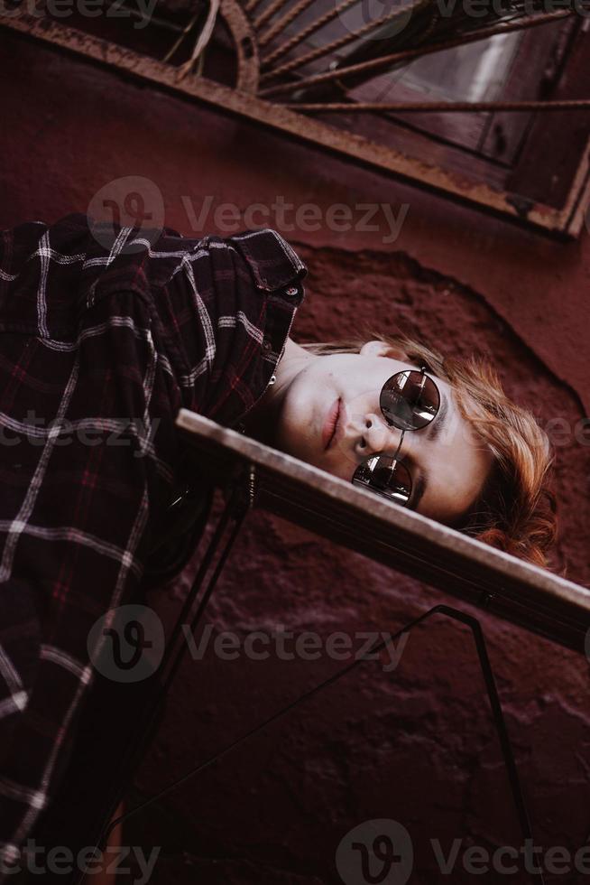 Woman with short red hair in sunglasses, head lies on table photo