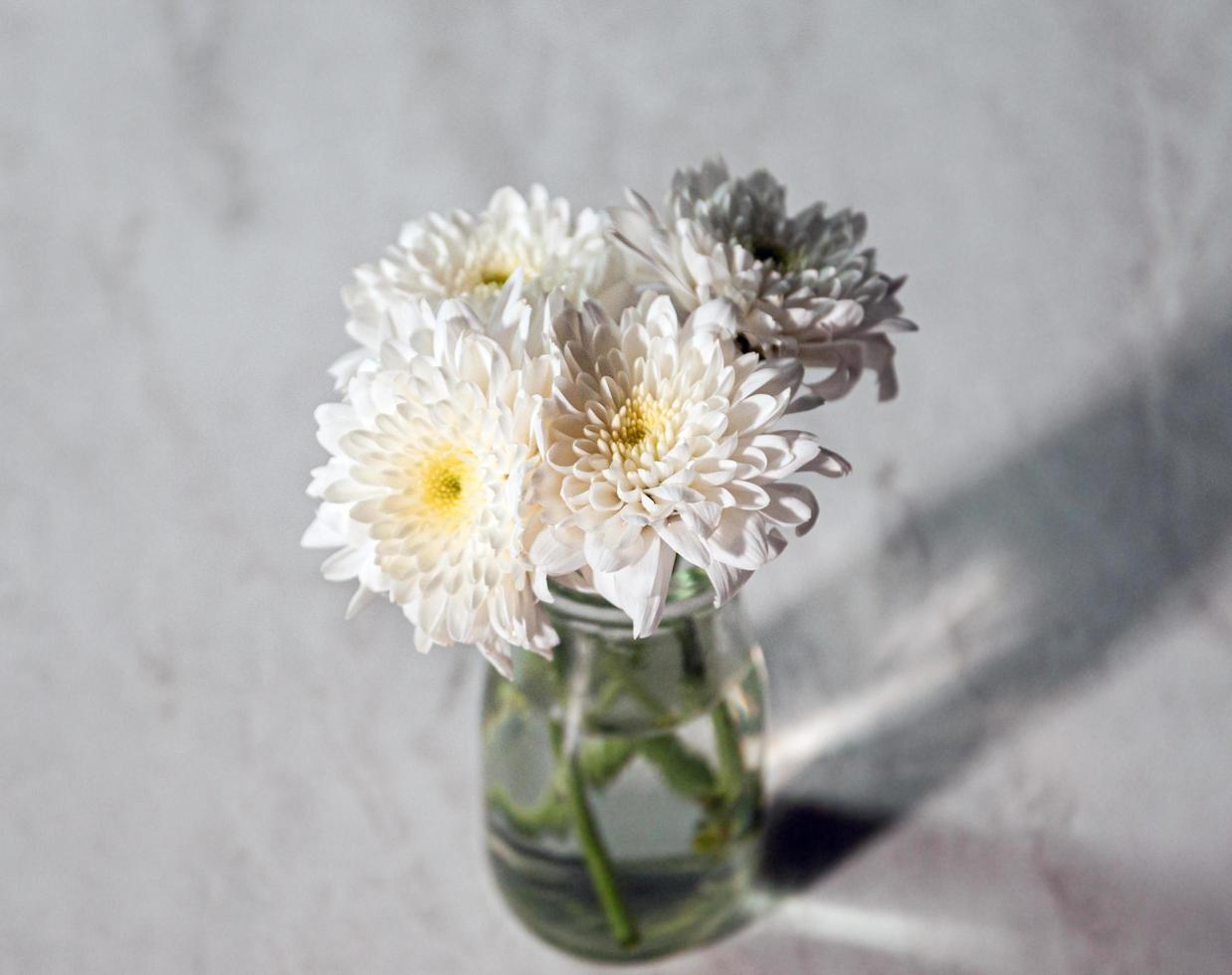 Ramo de flores blancas en un jarrón sobre la mesa de madera foto