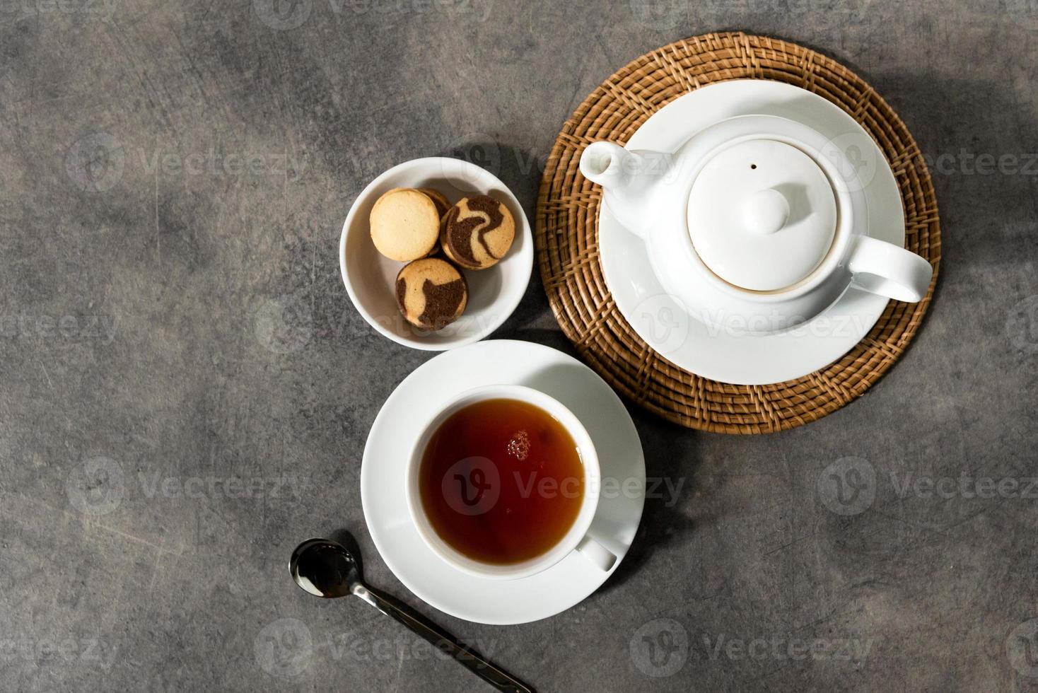 Taza de té de porcelana blanca y tetera, té inglés en la mesa foto