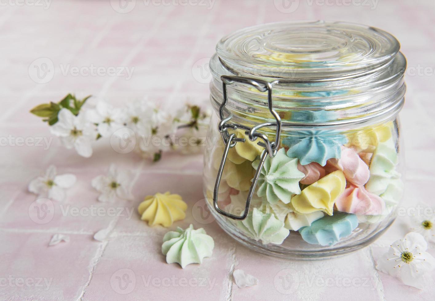 Small colorful meringues in the glass jar photo