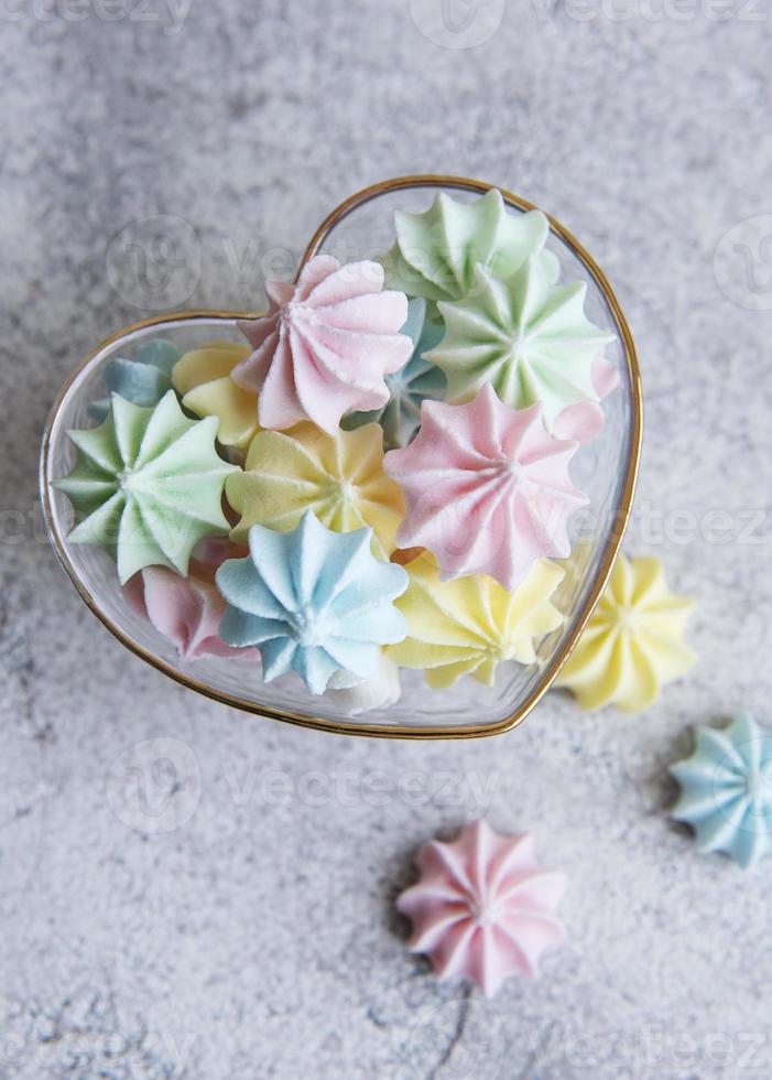 Small colorful meringues in the  heart shaped bowl photo