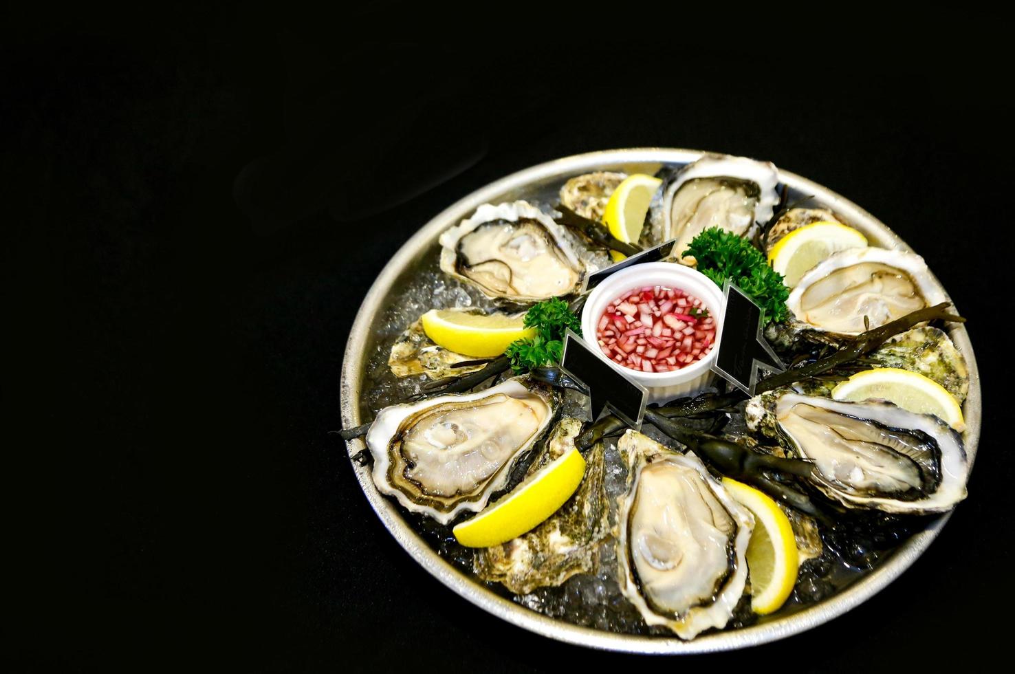 Fresh oysters on a plate with ice and lemon slices photo