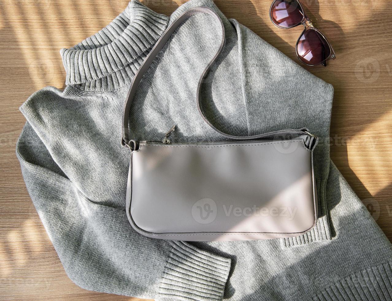 Small beige leather bag and gray women's sweater photo