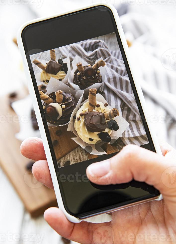 Girl makes a photo of cupcakes on a smartphone