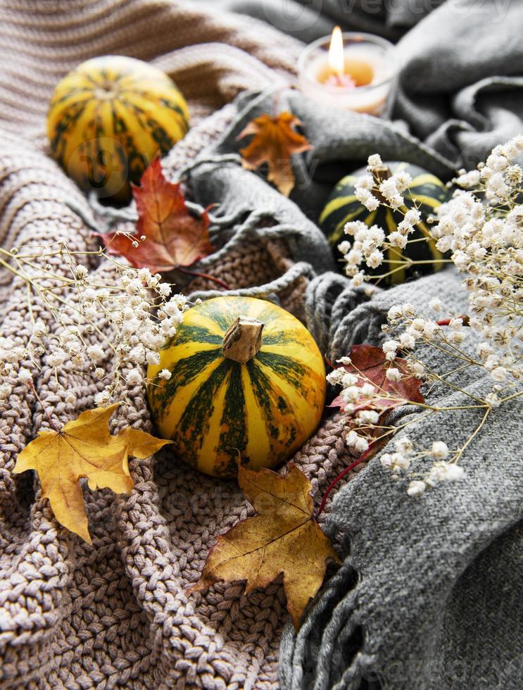 Autumn pumpkins, knitted scarf, maple leaves and candle. photo