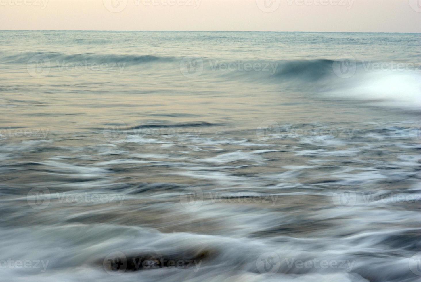 turbulencia de agua de mar y rocas en la costa foto