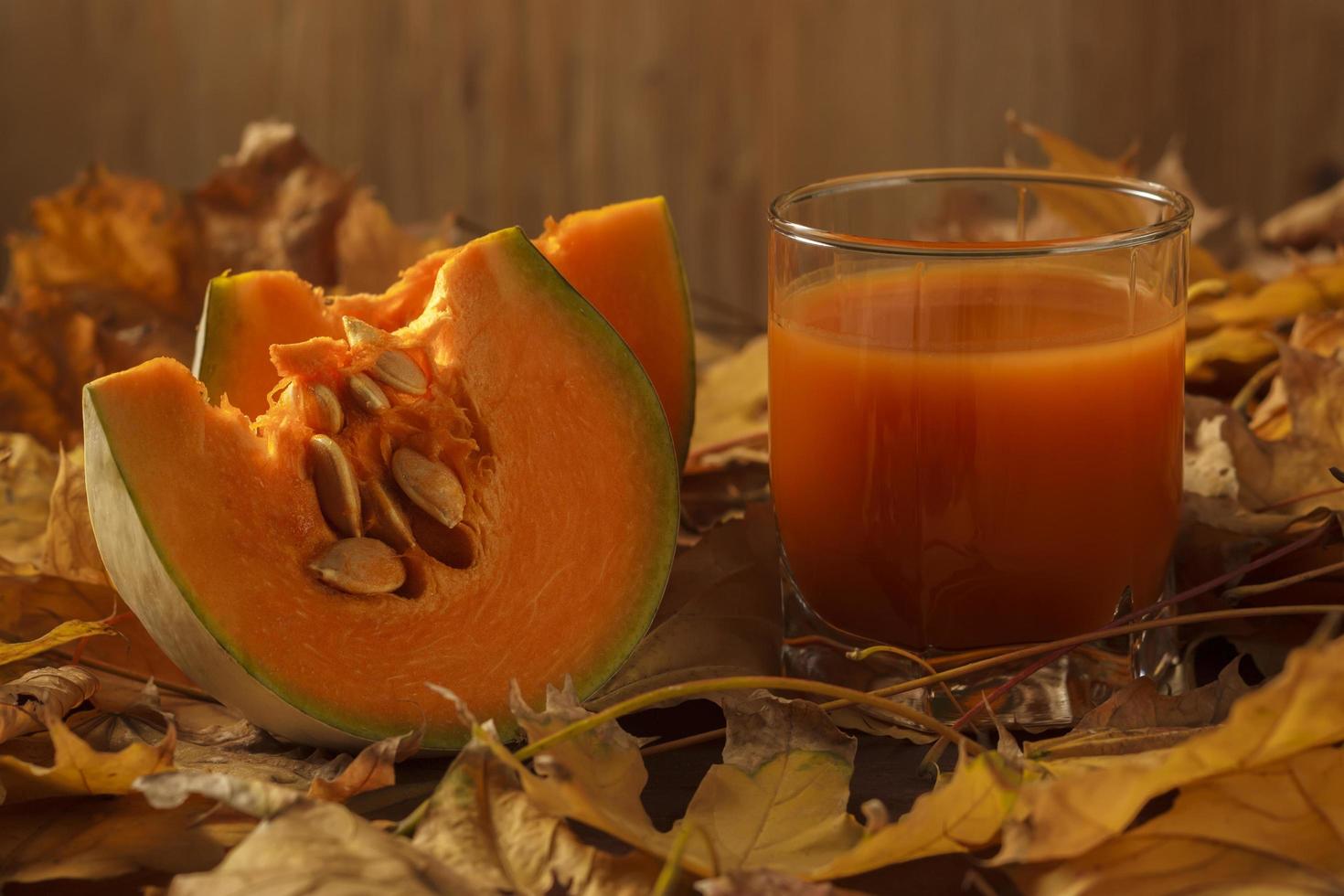 A whole pumpkin and a piece with juice against foliage photo