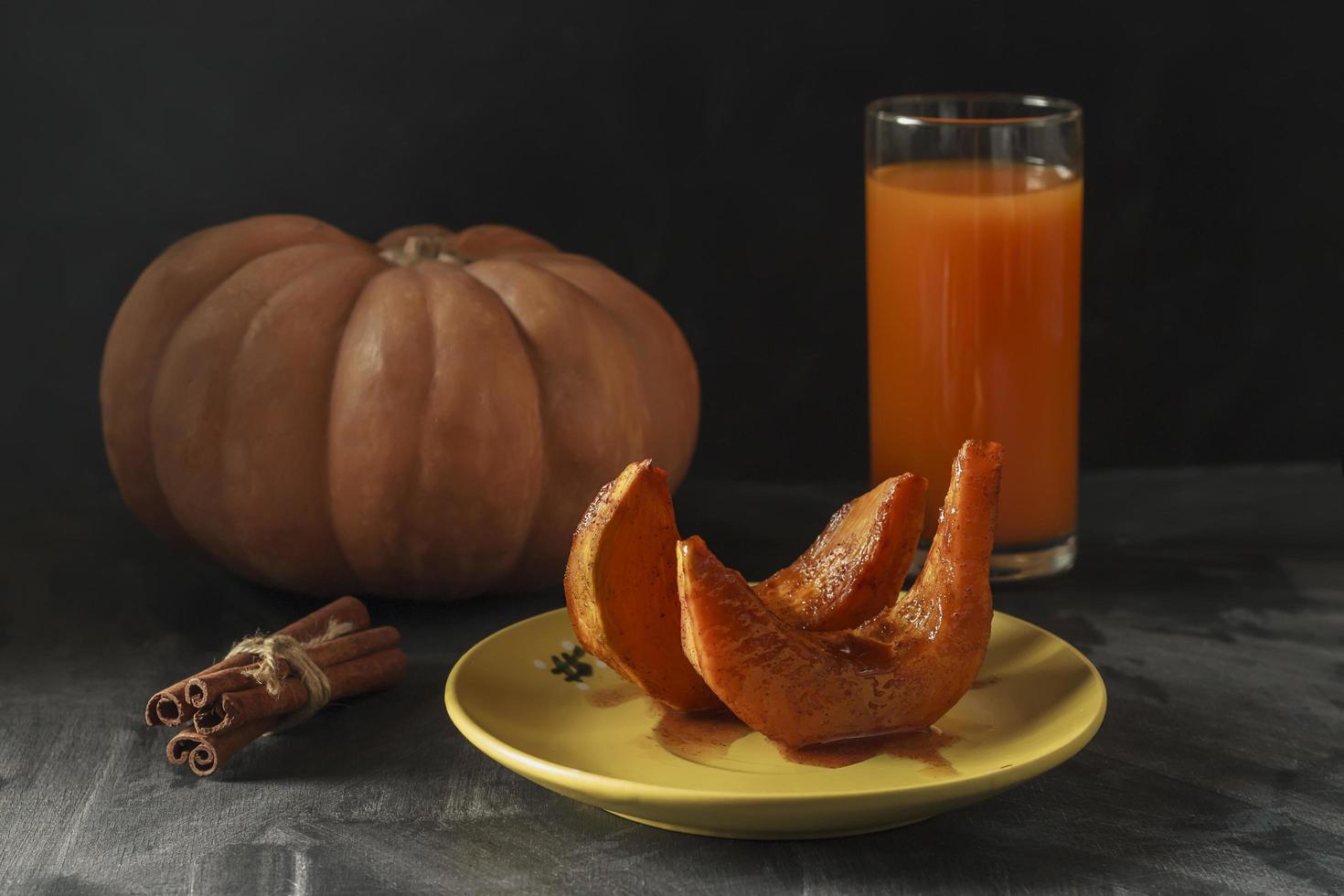 calabaza asada con palitos de canela, cuchara rústica y un vaso de jugo foto