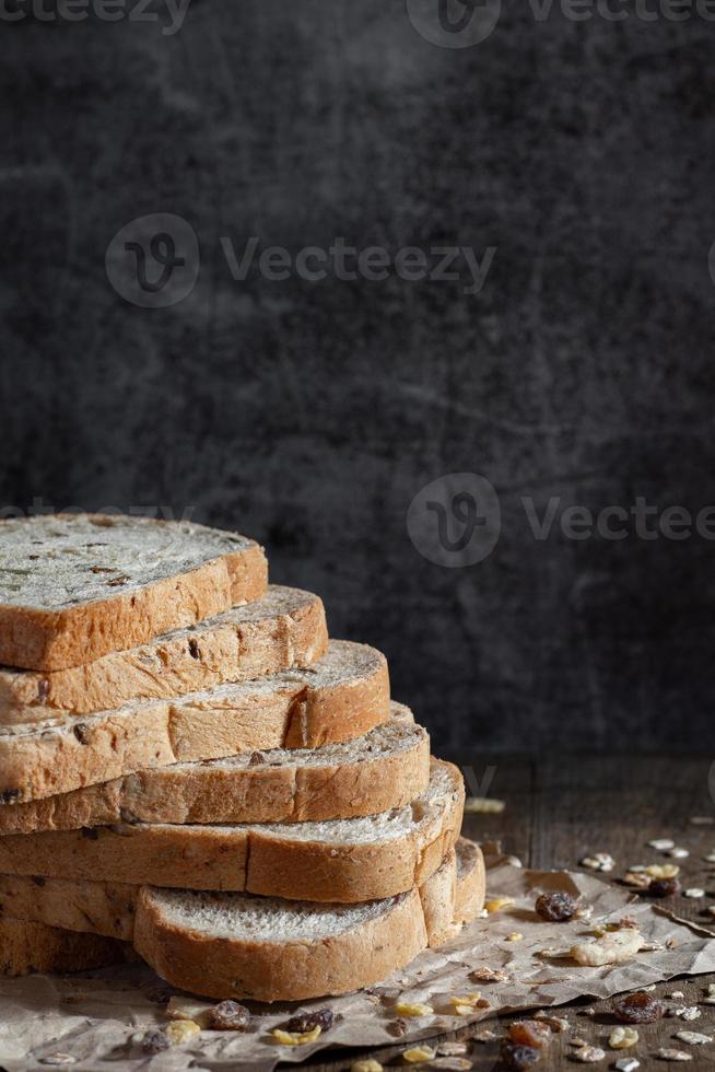 Primer plano de pan de trigo integral de grano en rodajas sobre fondo oscuro foto