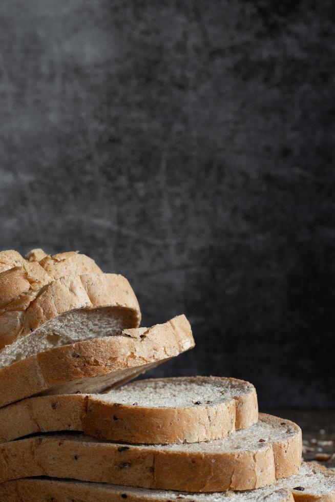 Primer plano de pan de trigo integral de grano en rodajas sobre fondo oscuro foto