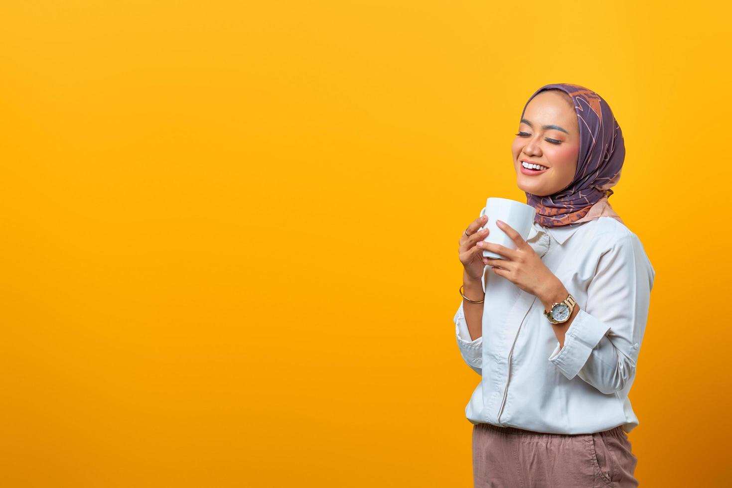 Hermosa mujer asiática sonriendo y sosteniendo la taza con espacio en blanco foto