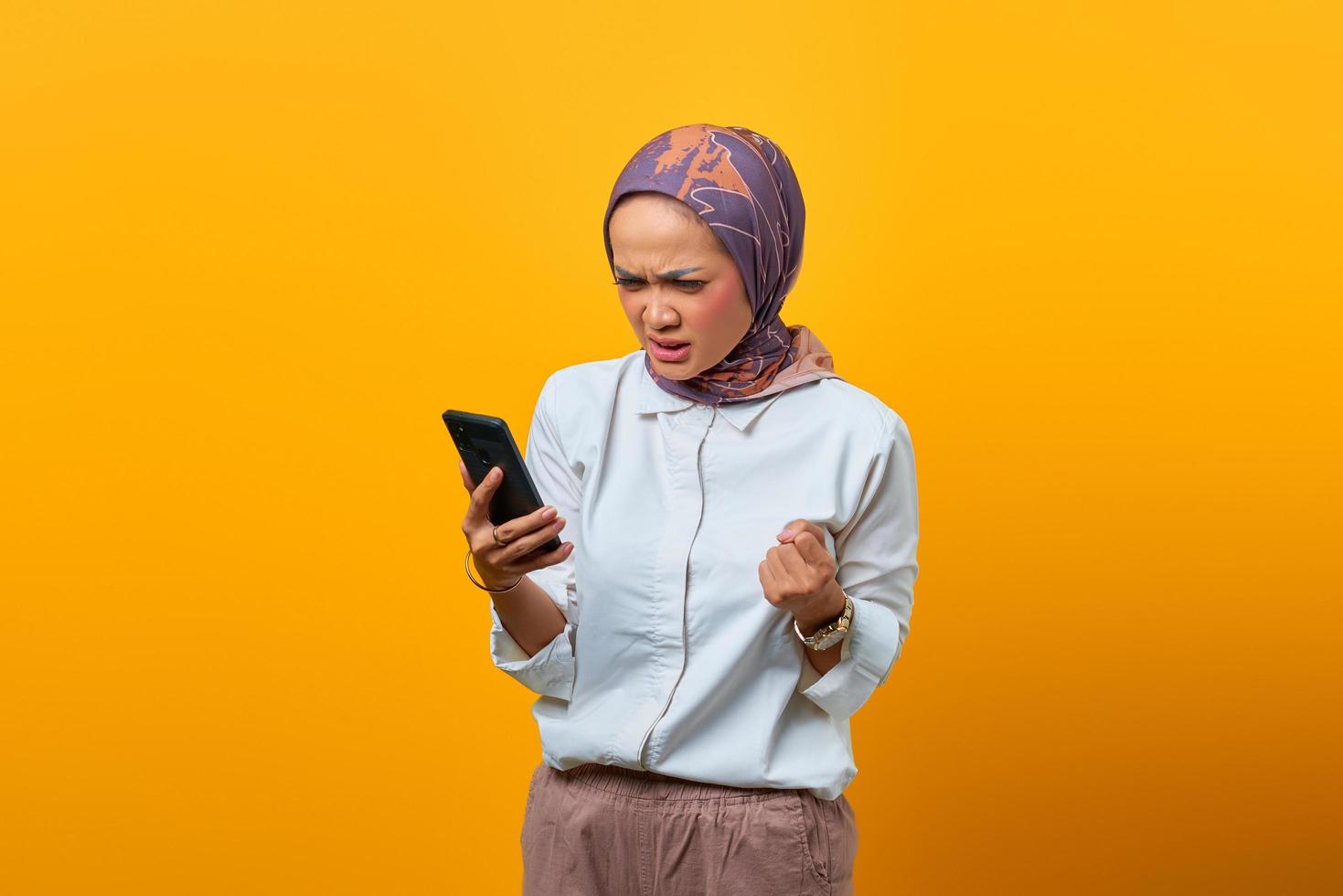 Mujer asiática enojada mirando smartphone recibiendo malas noticias foto