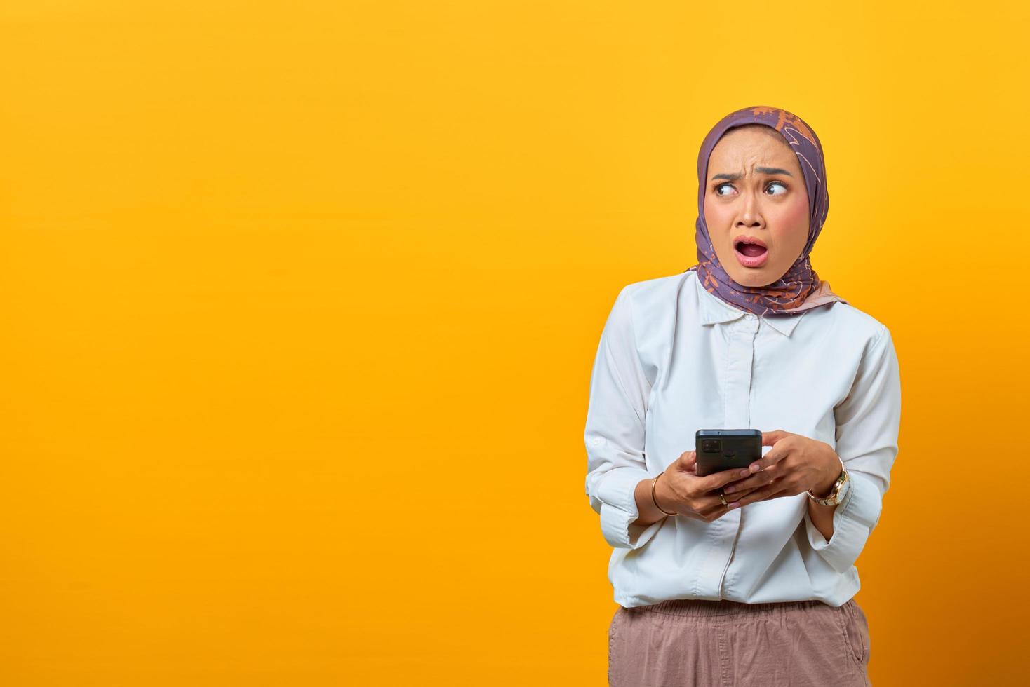 Shocked Asian woman holding smartphone with open mouth photo