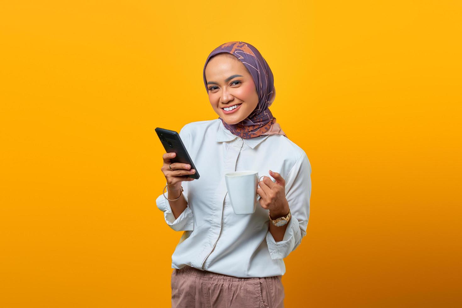 Happiness Asian woman relaxing holding mug and using mobile phone photo