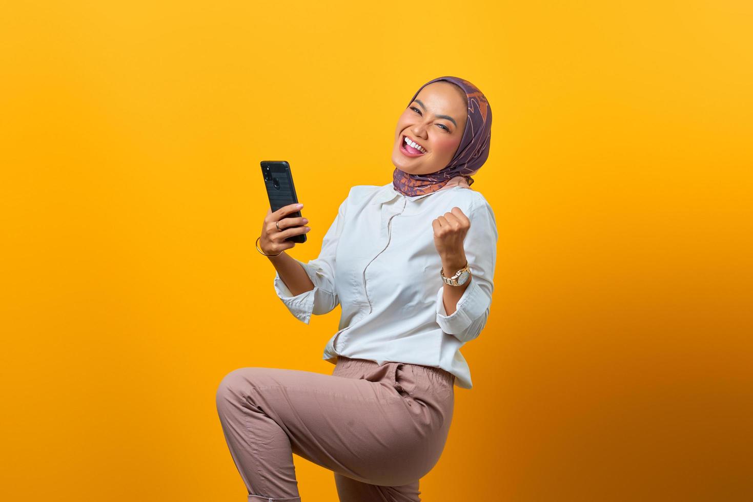 Excited Asian woman holding mobile phone celebrating luck photo