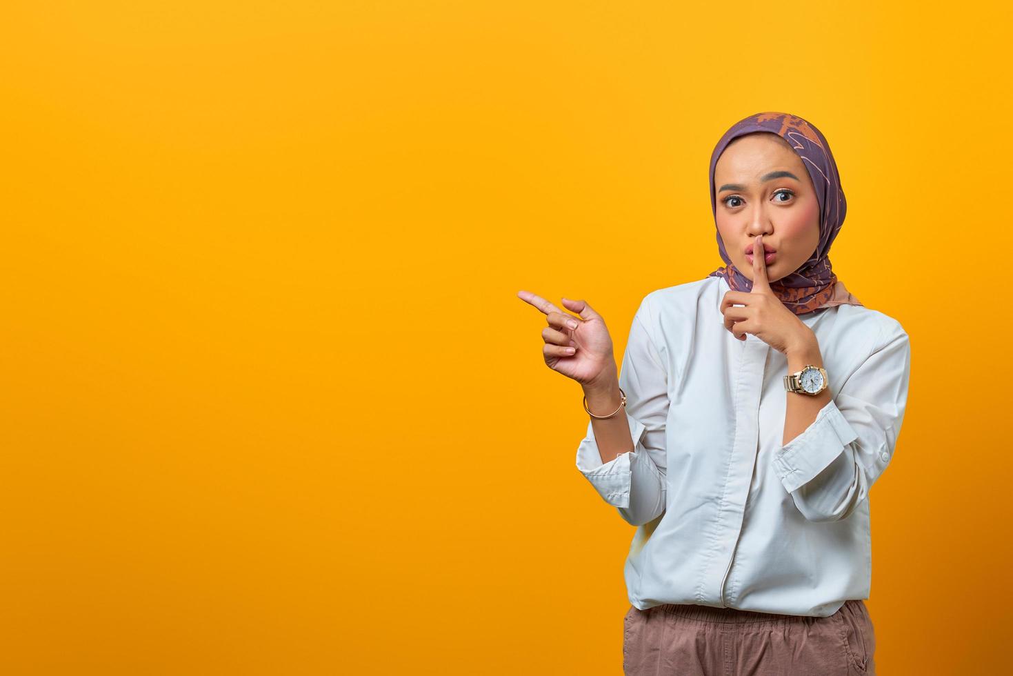 Beautiful Asian woman signal to silence and pointing to the side photo