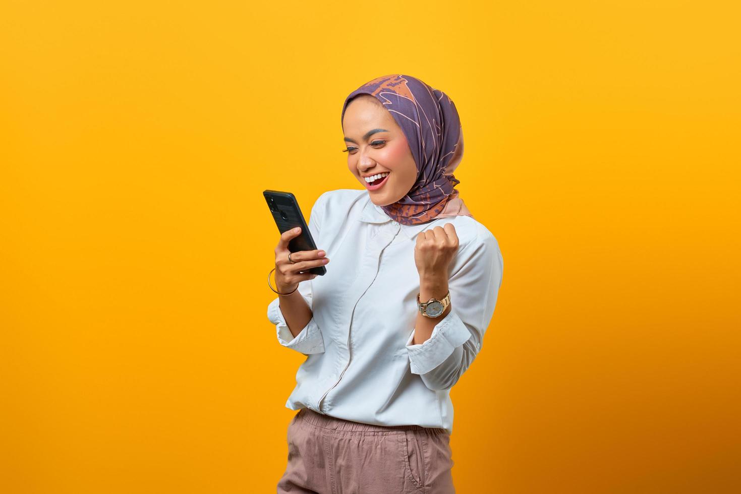 Excited Asian woman holding mobile phone celebrating luck photo