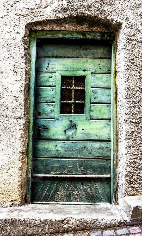 Puerta de madera verde con ventana dañada por el clima en San Martino di Castrozza, Trento, Italia foto