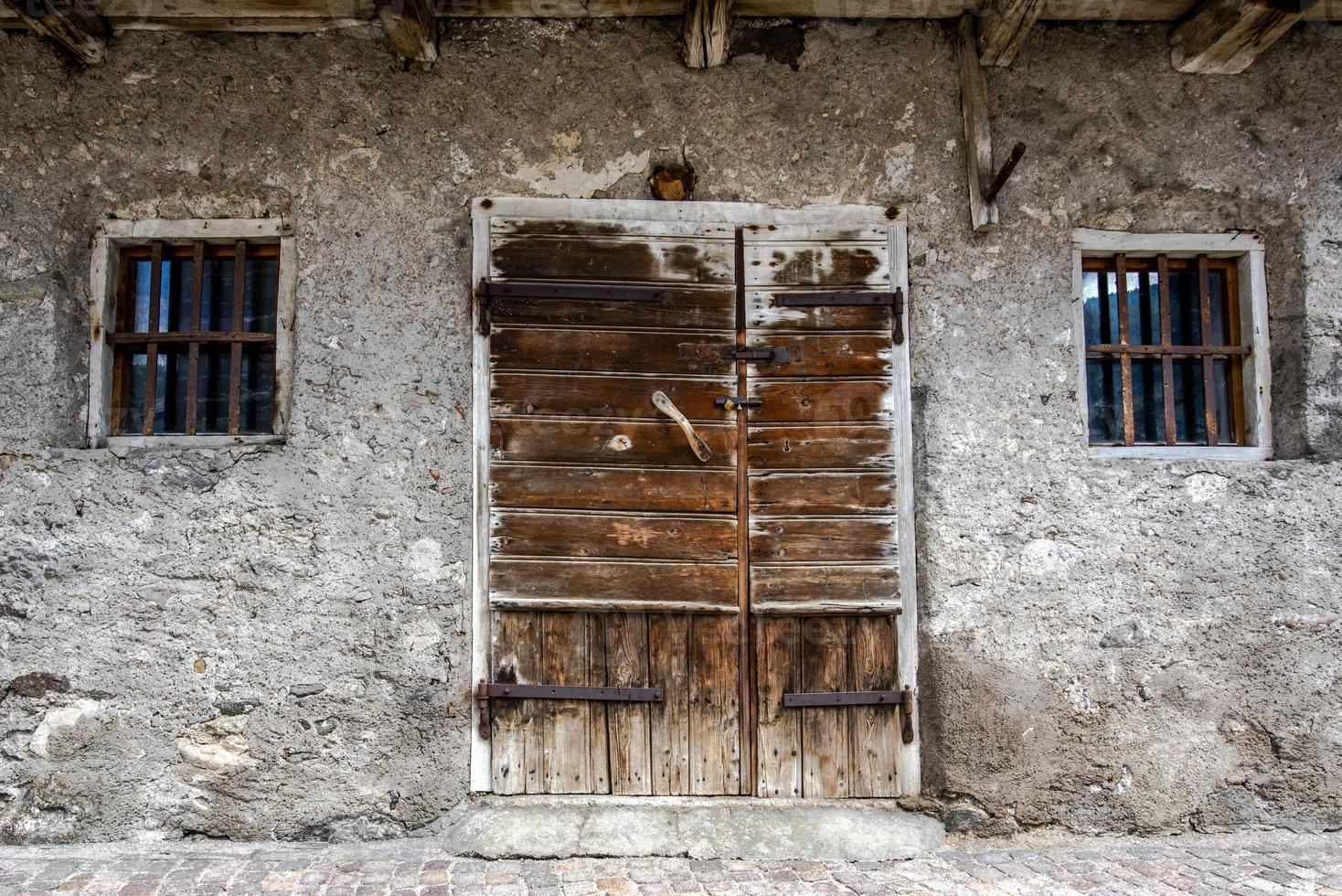 Antigua puerta de madera dañada por el clima en San Martino di Castrozza, Trento, Italia foto