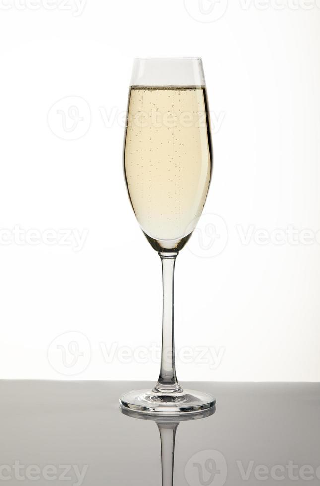Copa de champán sobre un fondo blanco con un sustrato gris foto