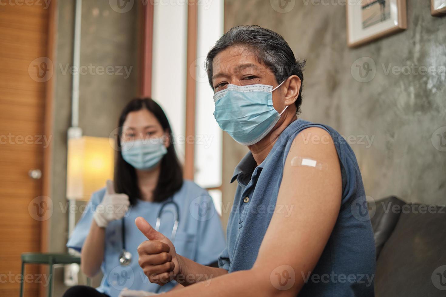 Elderly patient with face mask thumb up when vaccinated. photo