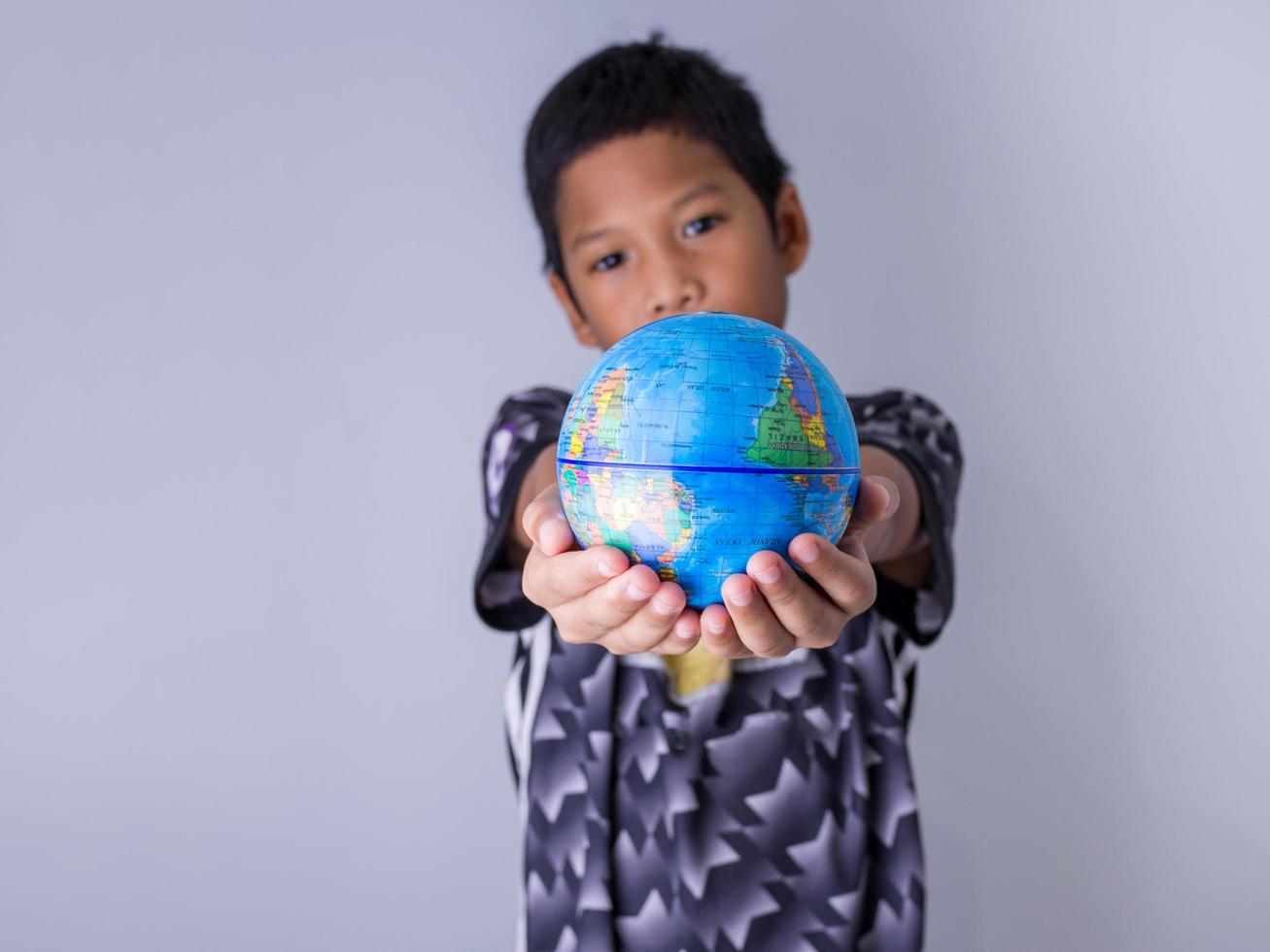 boy holding a globe stand out in front . photo