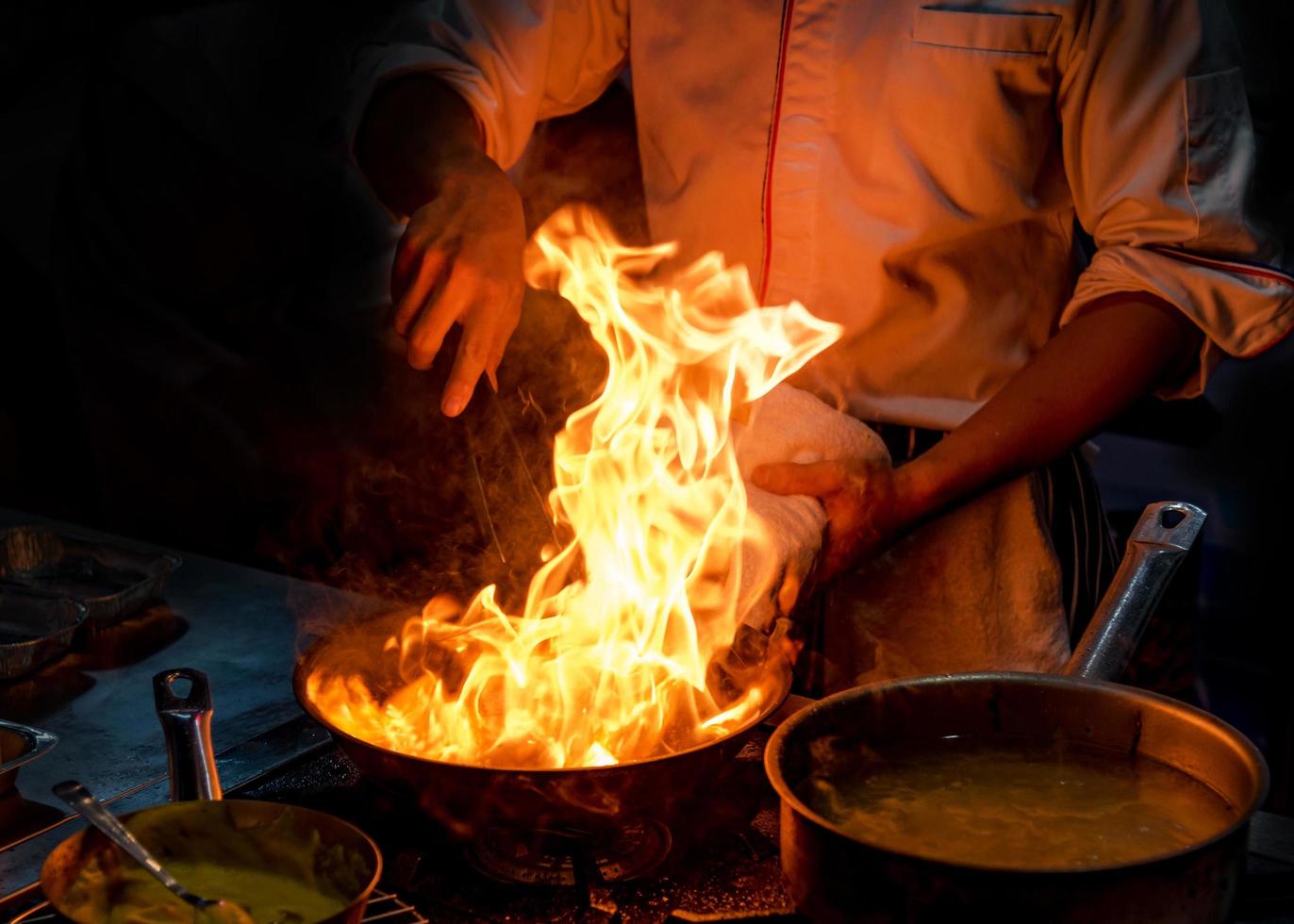 Chef cocinando con llama en una sartén sobre una estufa de cocina foto