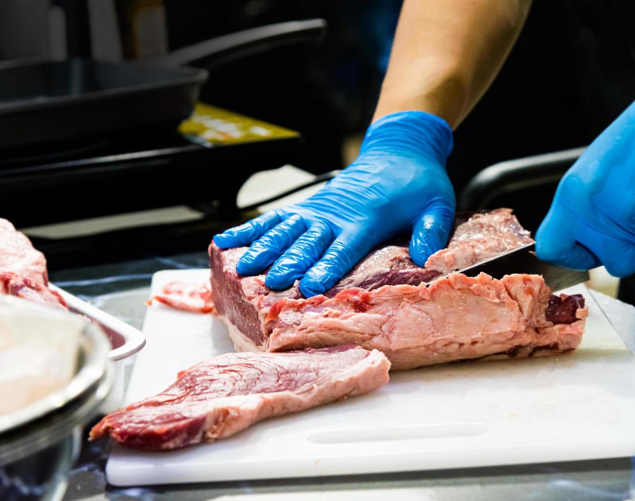 El chef corta la carne cruda con un cuchillo en una tabla, el cocinero corta la carne cruda foto