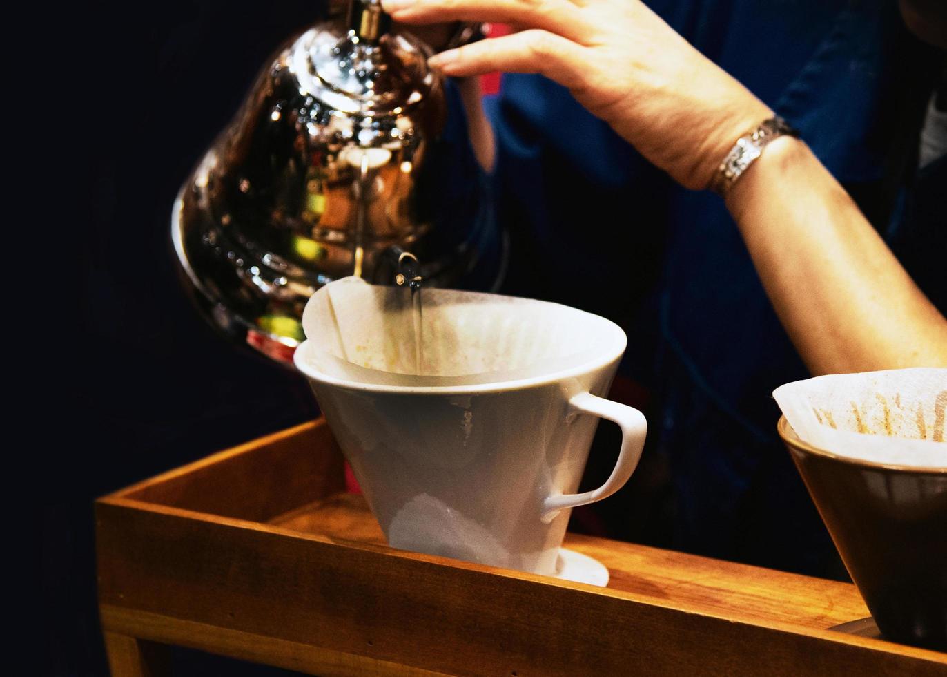 barista haciendo café, barista vertiendo café por goteo en un vaso foto