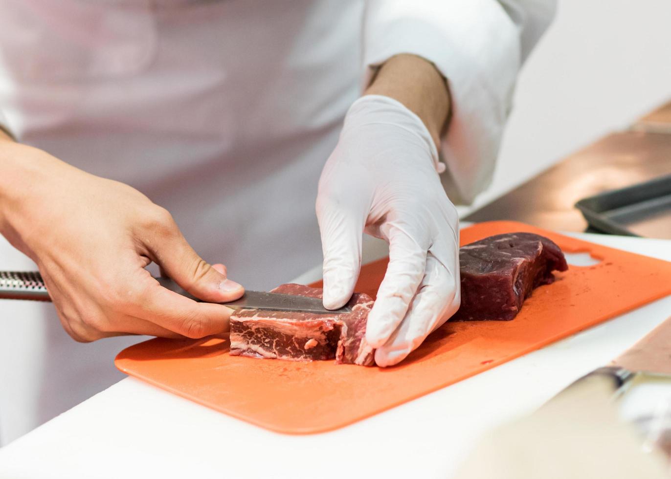 Chef cortando carne cruda fresca con un cuchillo en la cocina foto