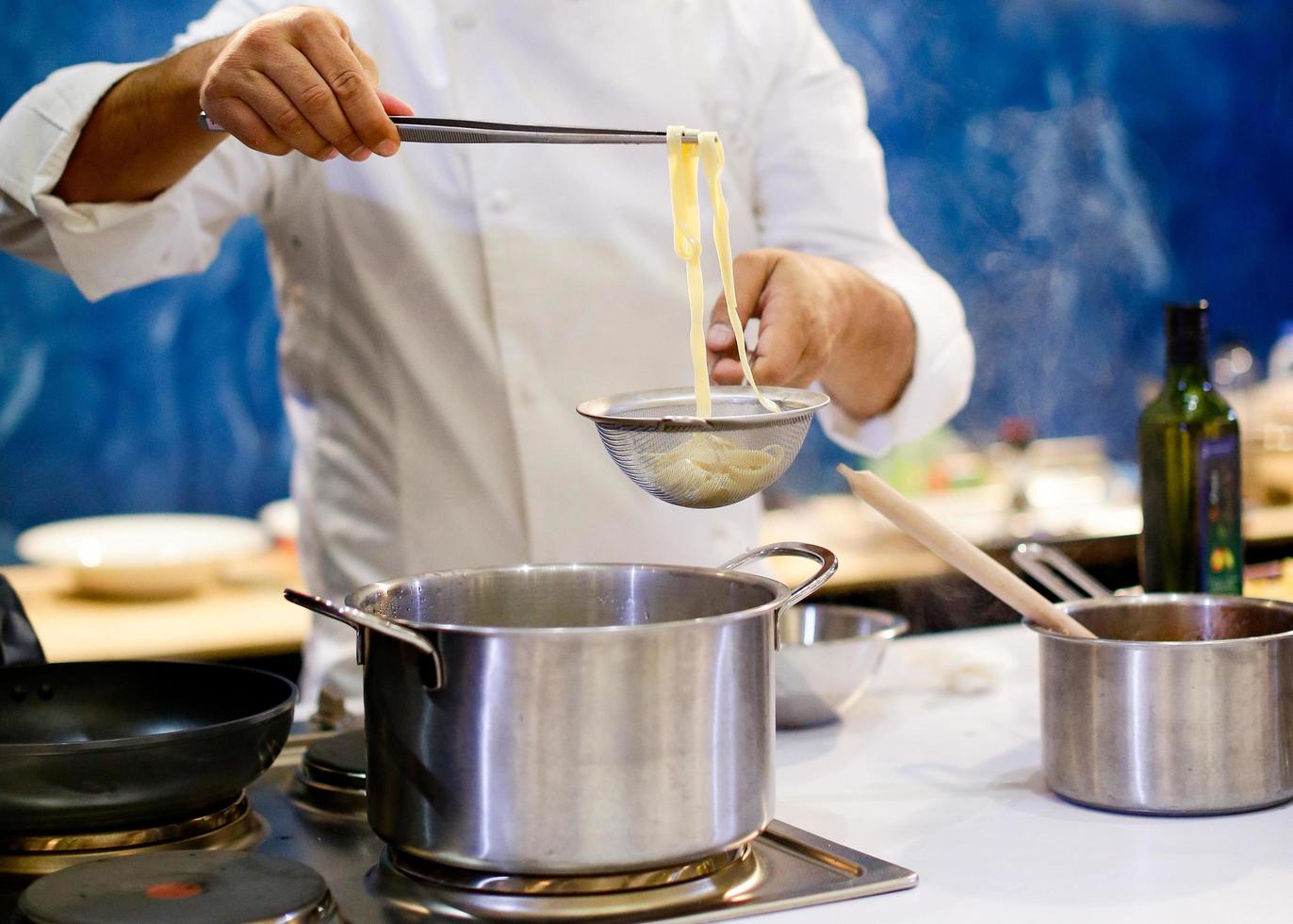 chef cocinando espaguetis en la cocina foto