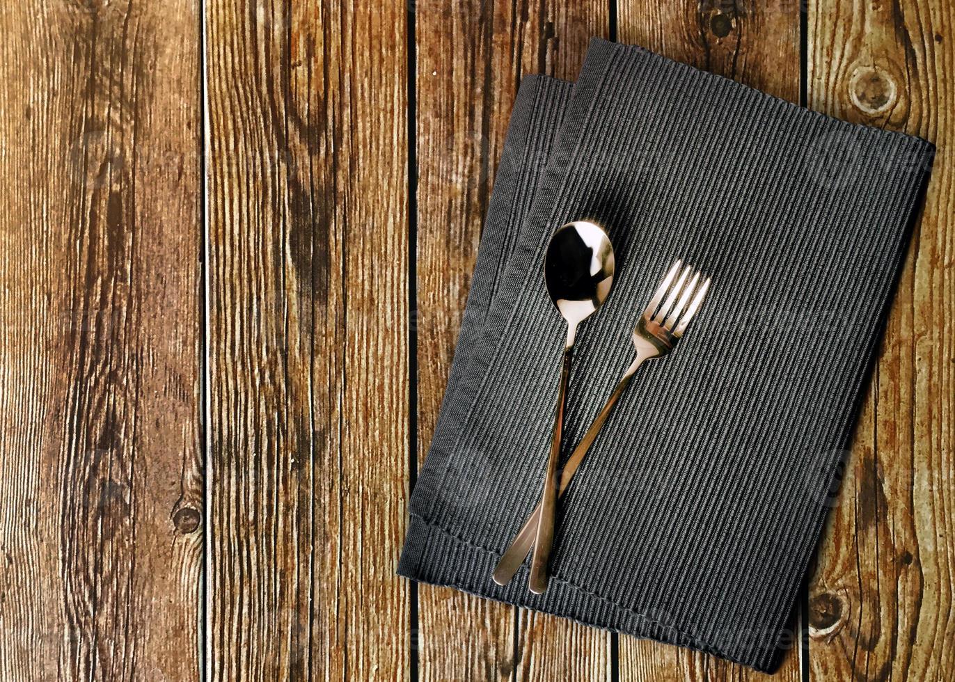 Fork and spoon serviette or napkin on wooden background photo