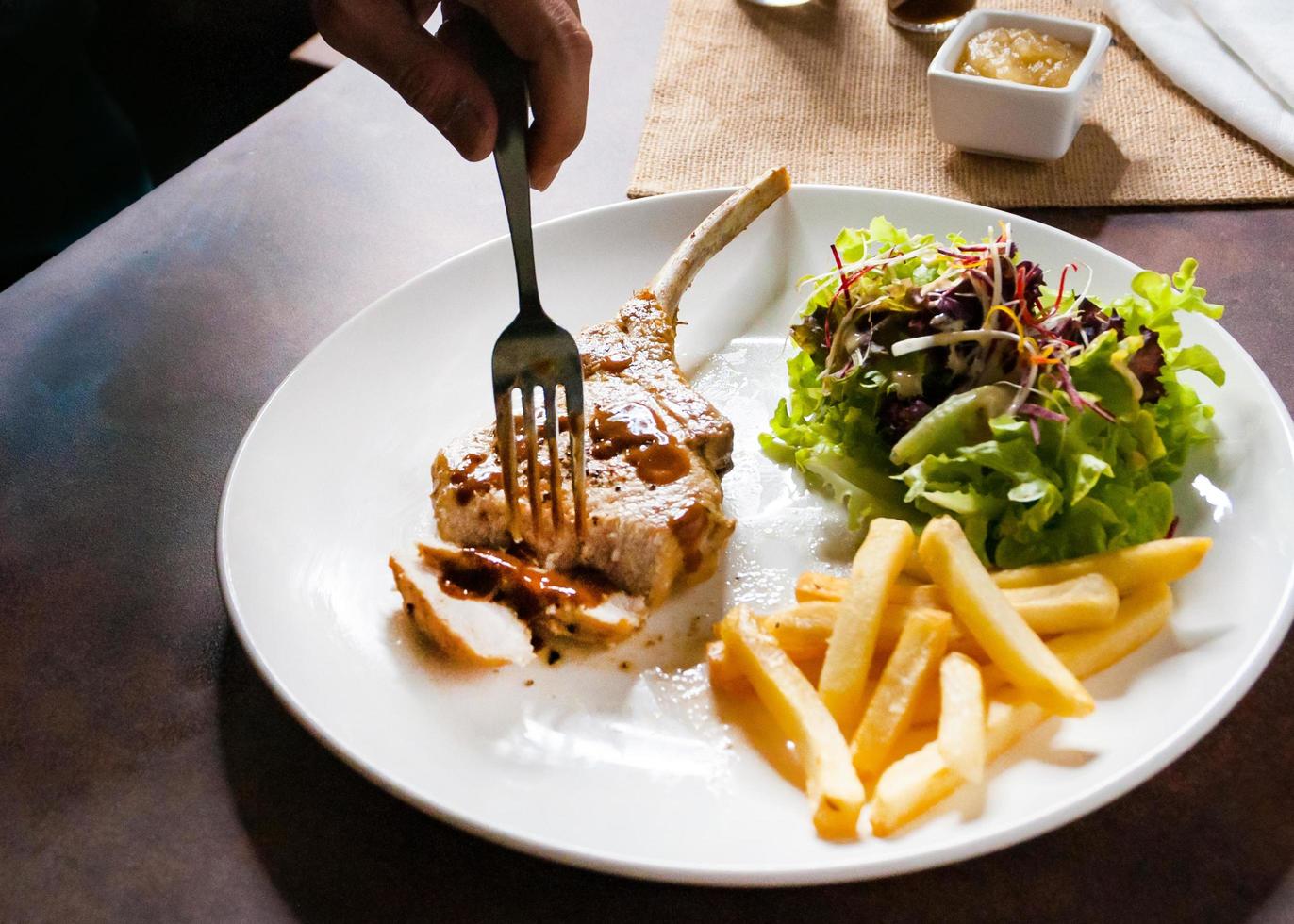 Chuletón de cerdo con ensalada y patatas fritas foto