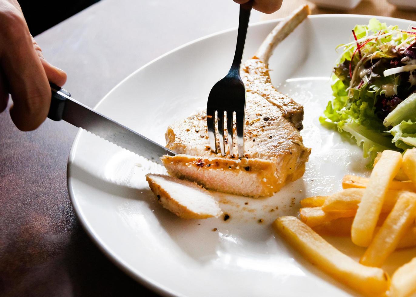 Chuletón de cerdo con ensalada y patatas fritas foto