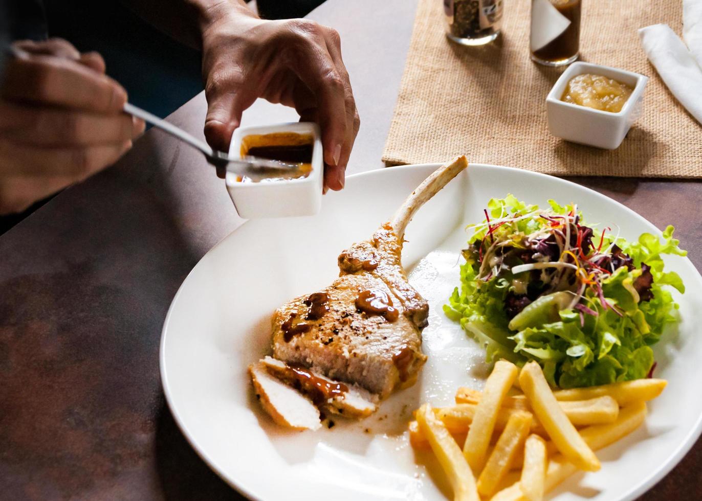 Chuletón de cerdo con ensalada y patatas fritas foto