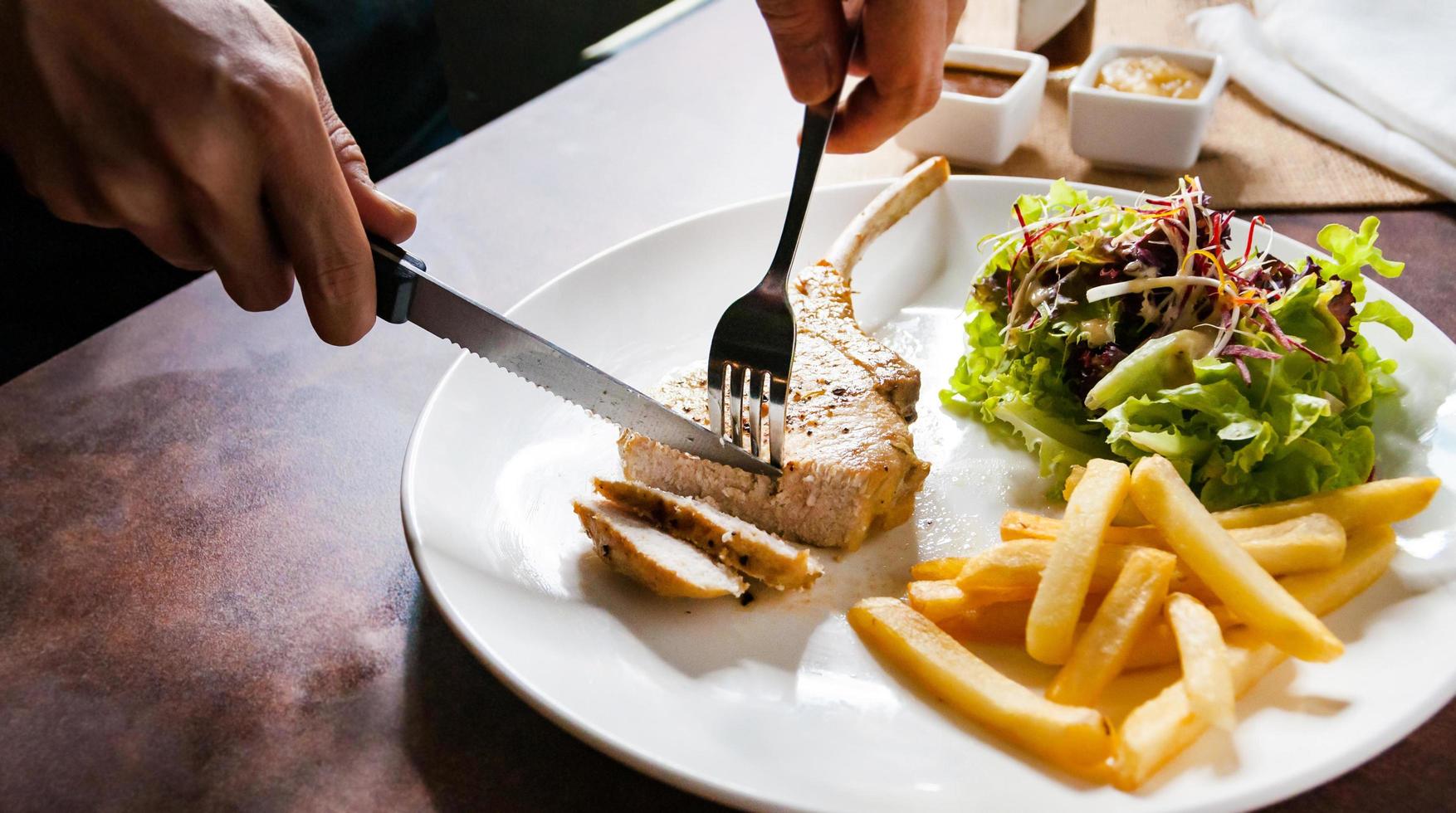 Chuletón de cerdo con ensalada y patatas fritas foto