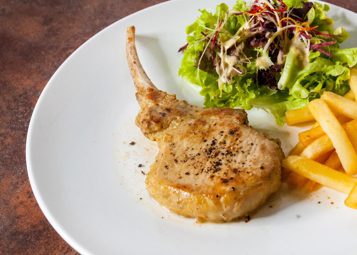 Pork chop steak with salad and french fries photo