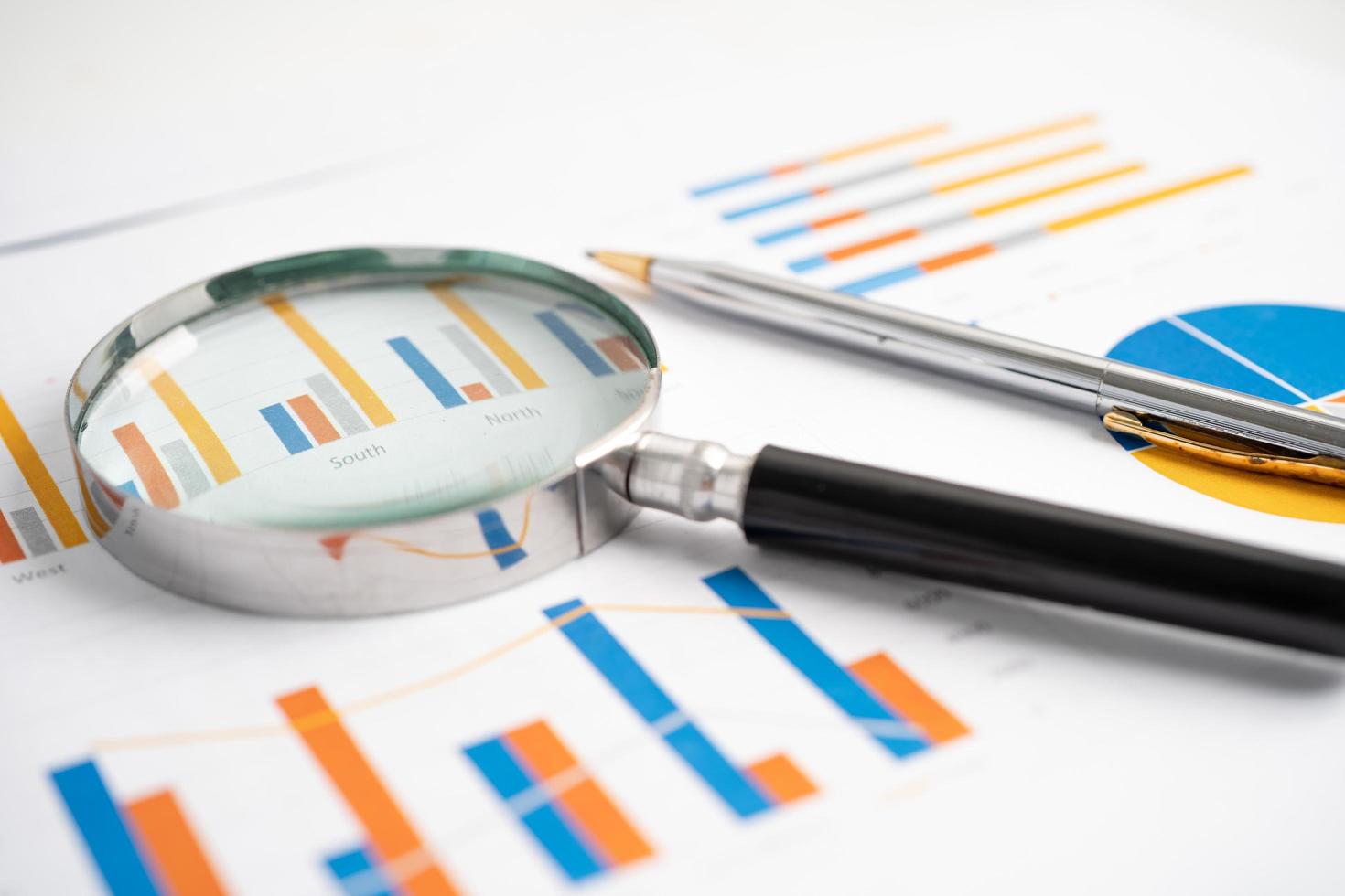 Magnifying glass on charts graphs paper. photo