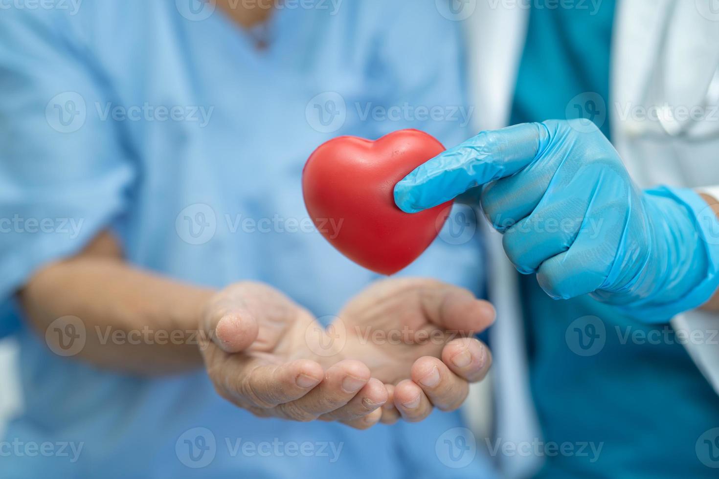 El doctor le da un corazón rojo al paciente asiático de la mujer mayor foto