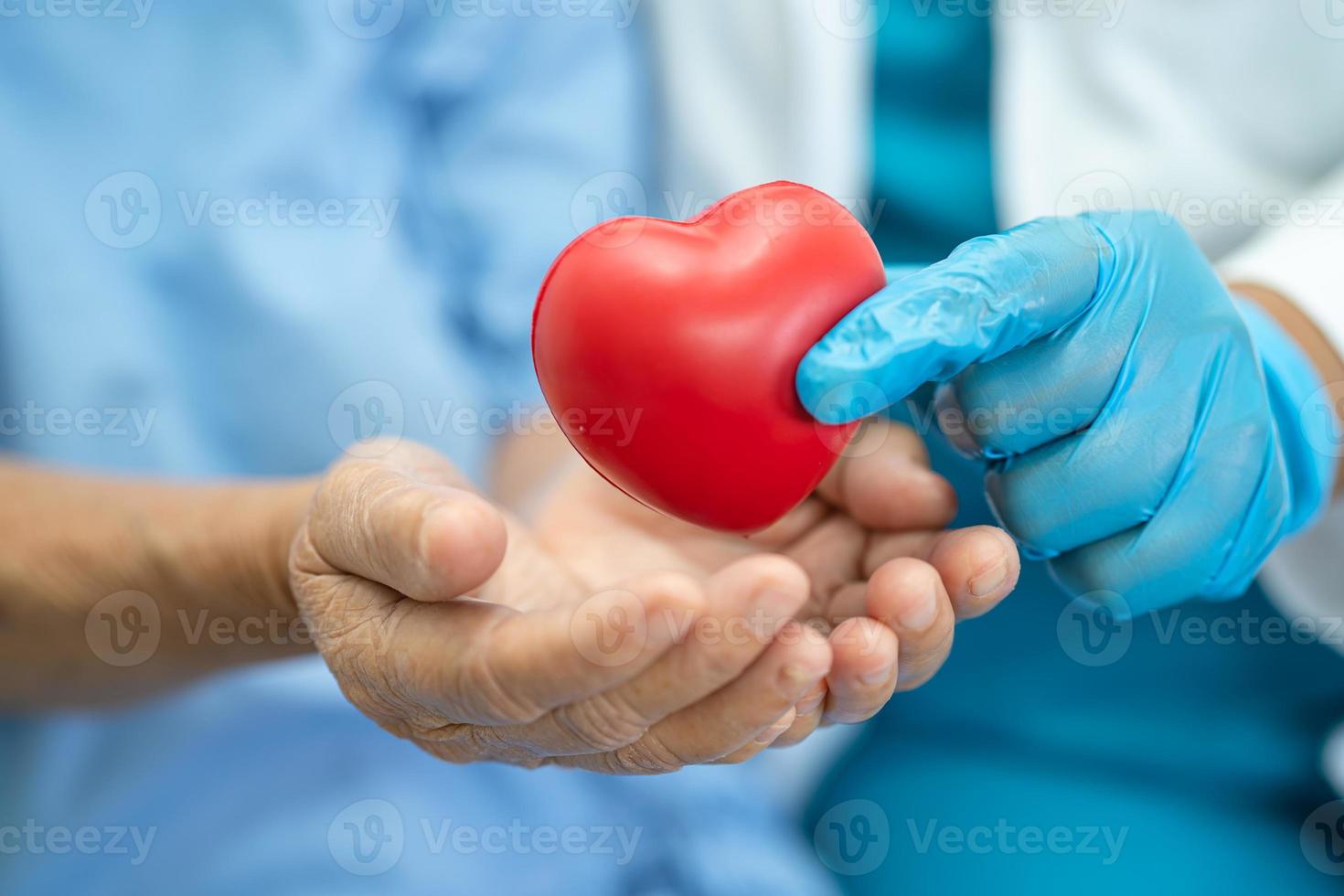 El doctor le da un corazón rojo al paciente asiático de la mujer mayor foto