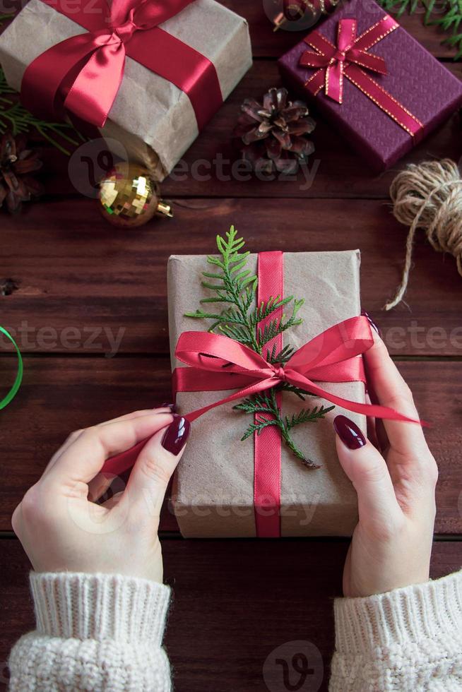 Wrapping Christmas gifts. Woman ties bow on the box. photo