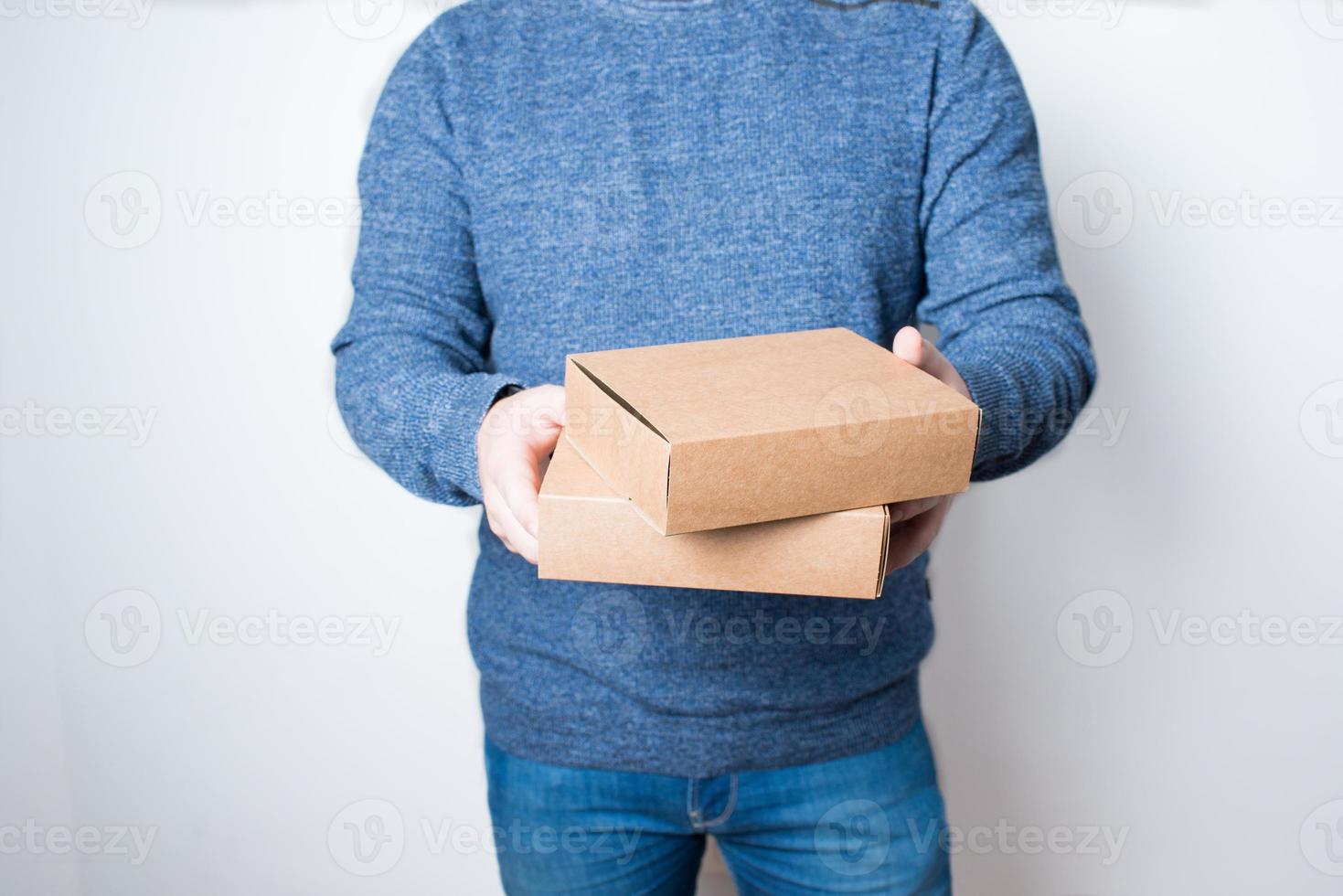 joven anónimo con jeans entregando dos cajas foto