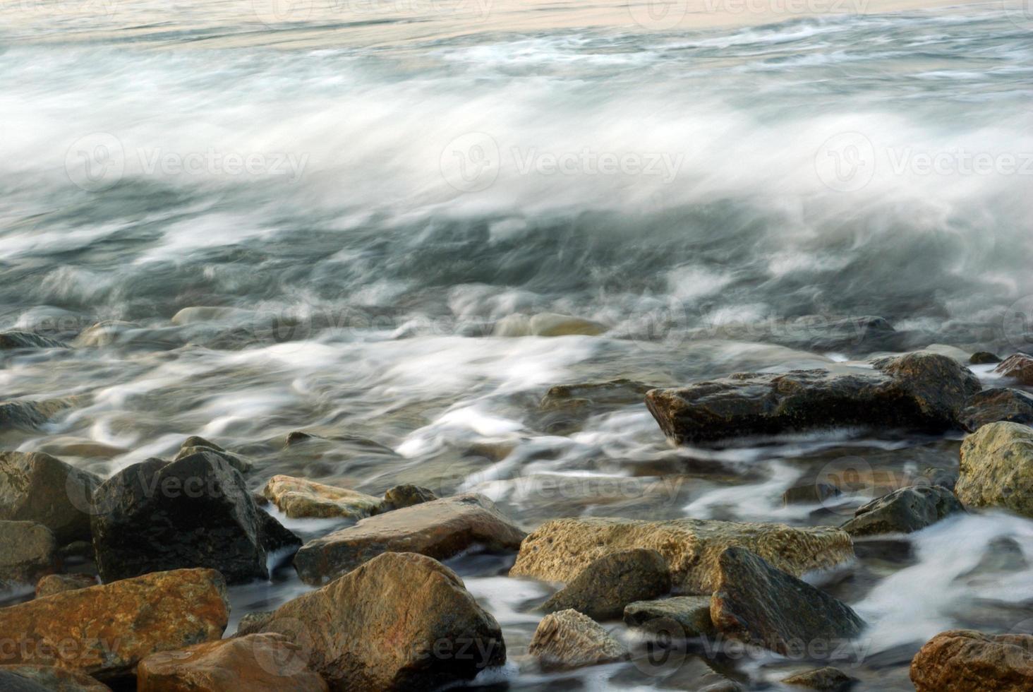 turbulencia de agua de mar y rocas en la costa foto