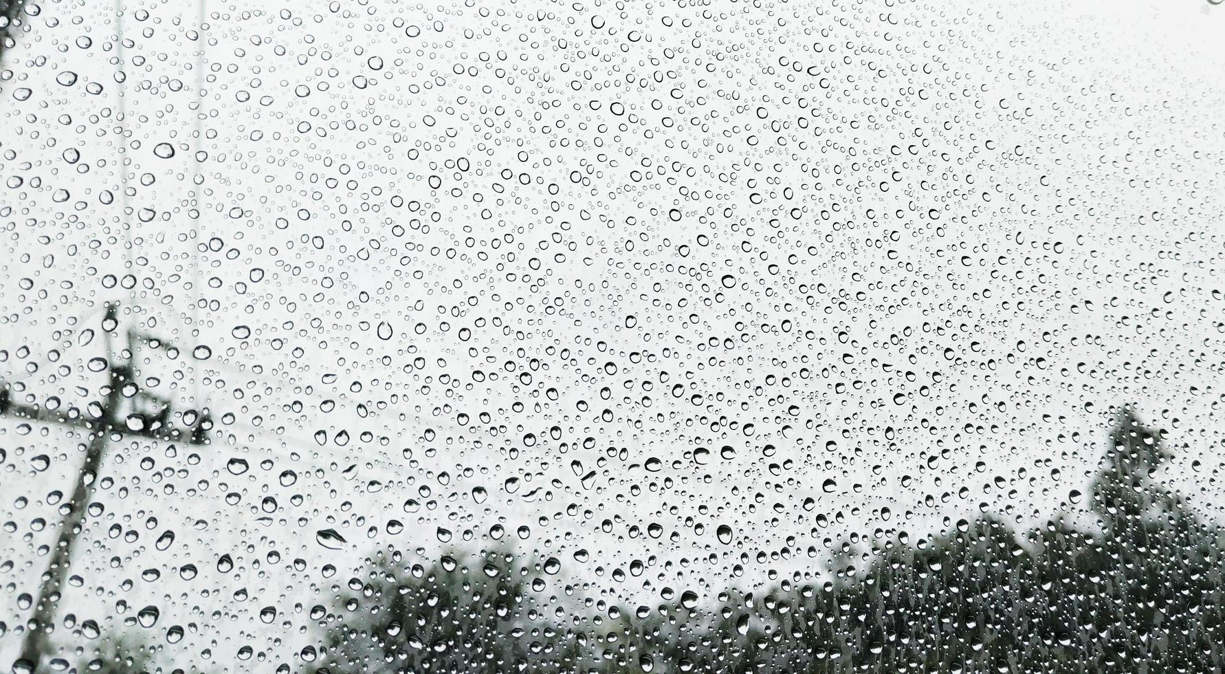 gotas de lluvia en el fondo de la ventana del coche foto